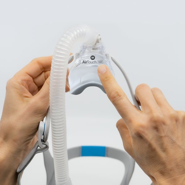 Hands seating an AirTouch N20 foam cushion into its frame, with the short tube attached