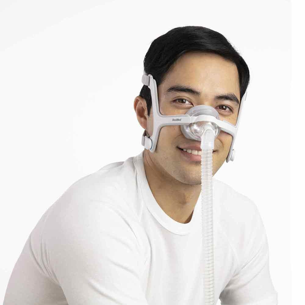 Smiling man wearing the AirTouch N20 nasal mask, its foam cushion resting around the nose