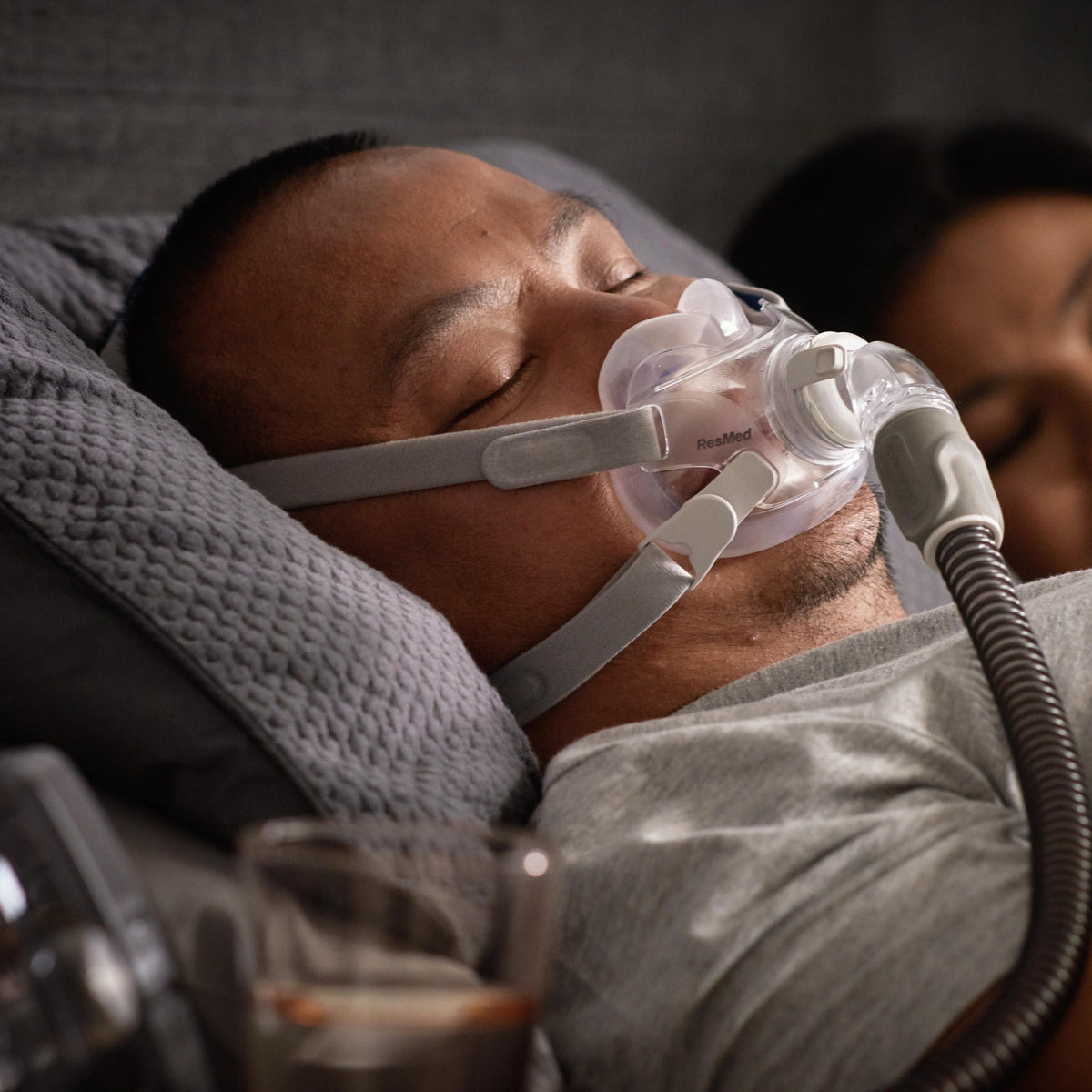 Photo of a man asleep on his side in the AirFit F30, his partner sleeping behind him
