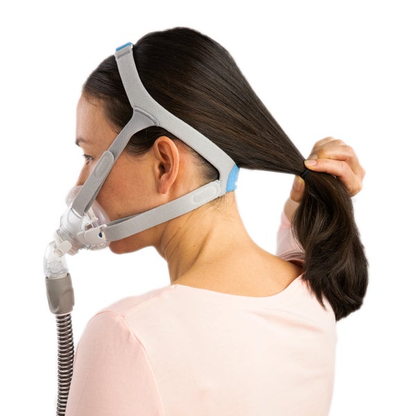 Side photo of a woman wearing the AirFit F30, pulling her ponytail through the back of the headgear
