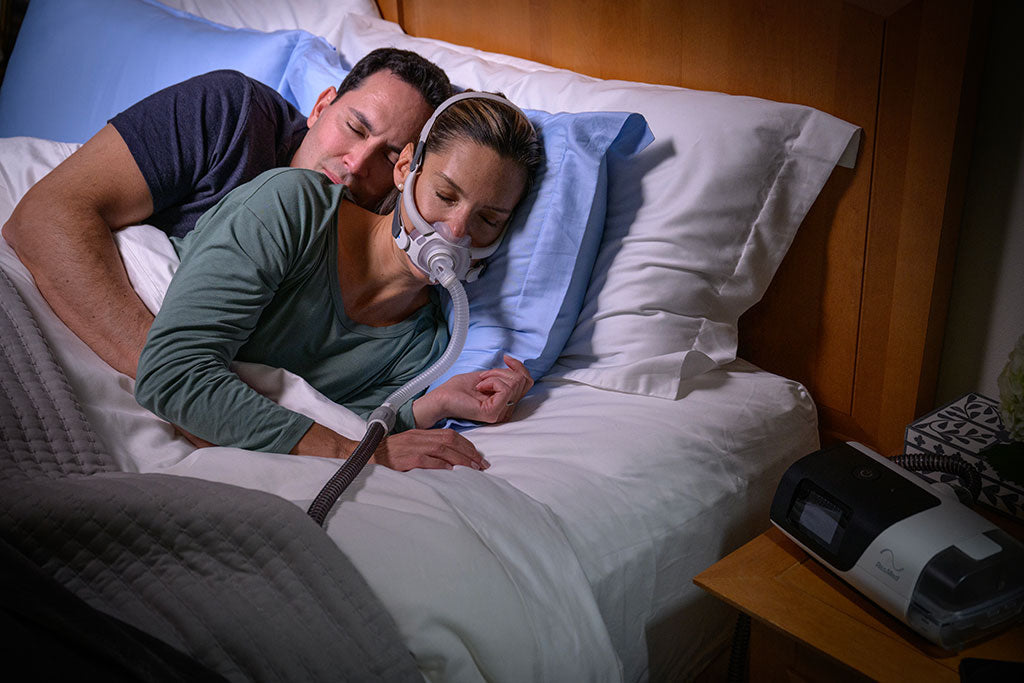 Photo of a couple in bed at night, the woman asleep in an AirFit F40 full face mask