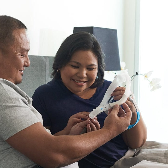 Photo of a couple sitting up in bed, holding an AirFit P30i frame and looking at it together