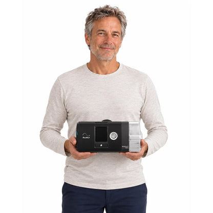 Photograph of a man in a light sweater holding the AirSense 10 AutoSet in both hands to show its size