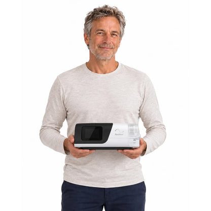 Photograph of a man in a light sweater holding the AirSense 11 AutoSet in both hands to show its size