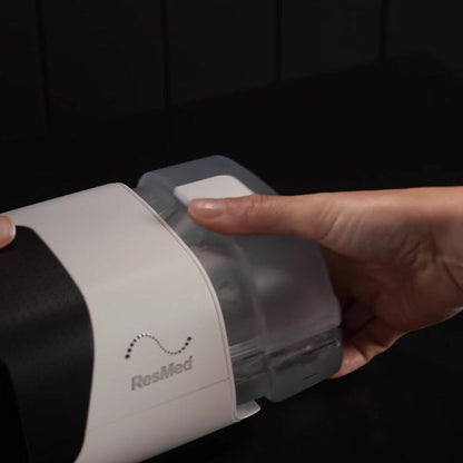 A hand slides the standard HumidAir 11 tub into the side of an AirSense 11 until it seats