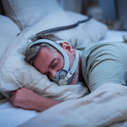Photo of a man asleep on his side in the AirTouch F30i, with the hose running up from his head