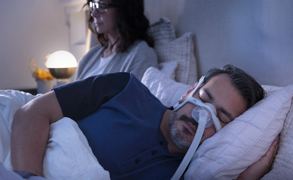 Photo of a man asleep on his side in the AirTouch N20 while his partner reads in bed beside him