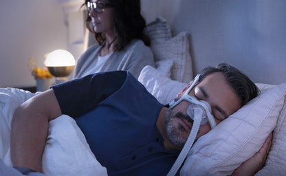Photo of a man asleep on his side in the AirTouch N20 while his partner reads in bed beside him