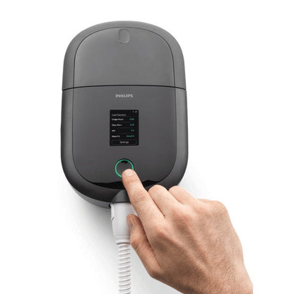 Top view of the Philips DreamStation 2 Auto CPAP Advanced, a finger pressing the therapy button below the colour touchscreen