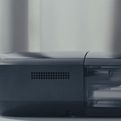 Studio photo of the DreamStation 2 Auto CPAP Advanced from the side, showing the air vents and clear water tank