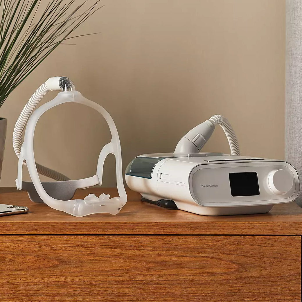 Bedroom photo of a DreamWear silicone pillows mask on a bedside table beside a CPAP machine
