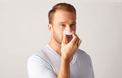 Photo of a man placing the DreamWear cushion under his nose as the first step of fitting