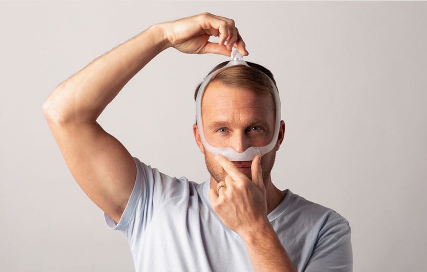 Photo of a man setting the DreamWear frame over the top of his head during fitting