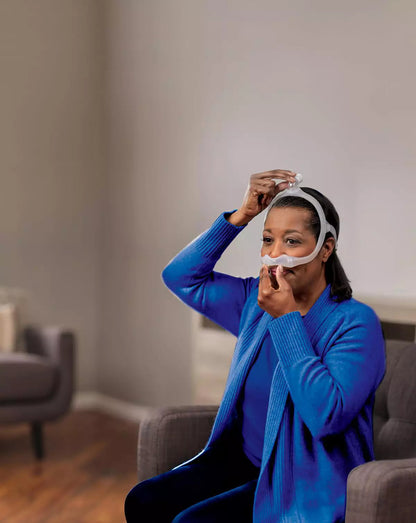 Photo of a woman in a blue sweater fitting the DreamWear, one hand at the pillows and one on top