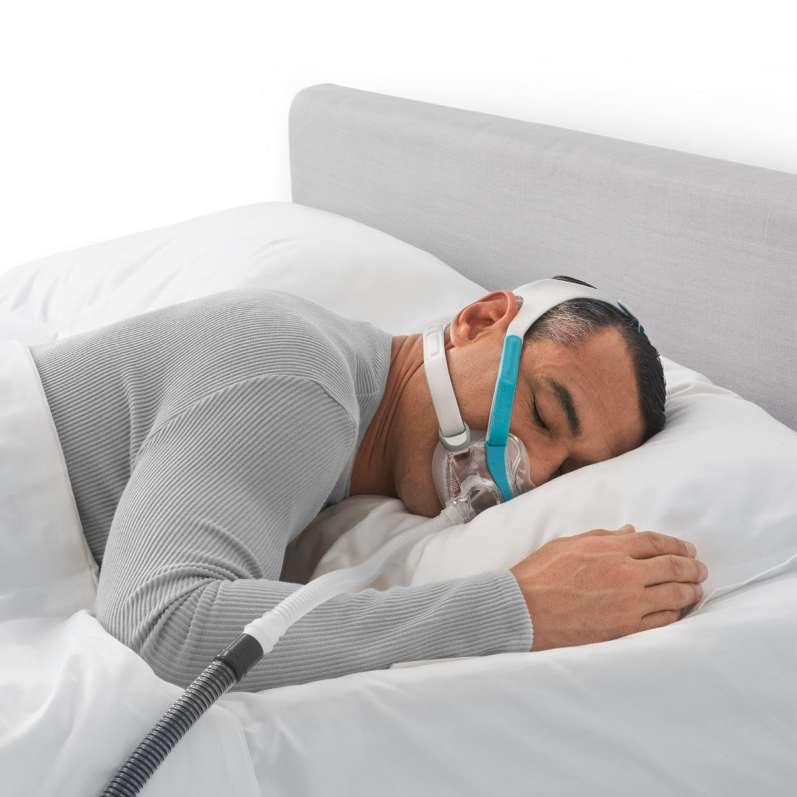 A man sleeping on his side in the Evora Full mask, the teal headgear holding the seal in place