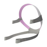 Angled view of the AirFit F10 For Her headgear, grey straps with a pink crown and four fastening tabs