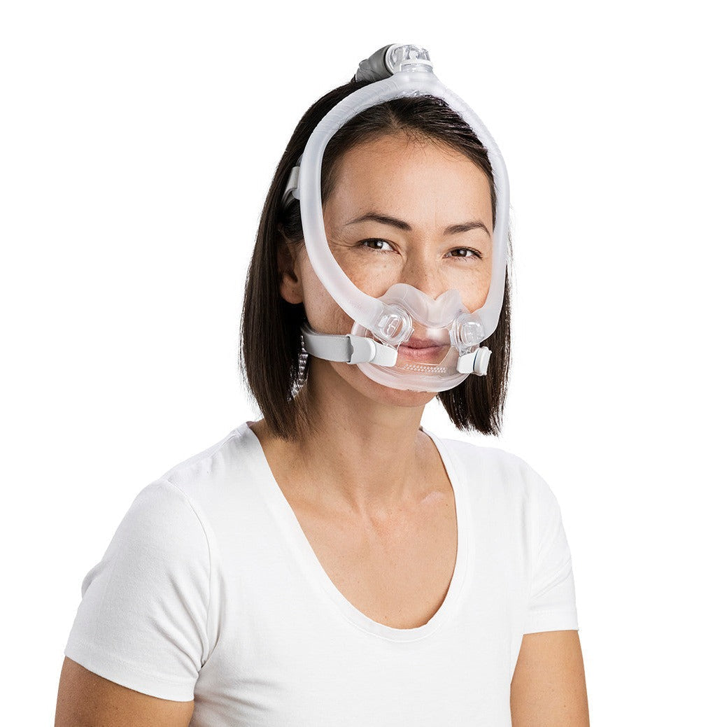 Woman wearing an AirFit F30i from the front, its frame rising over her head and the clips at her cheeks