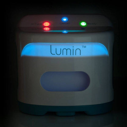 The Lumin sanitizer lit up in a dark room, its status lights and front window glowing softly