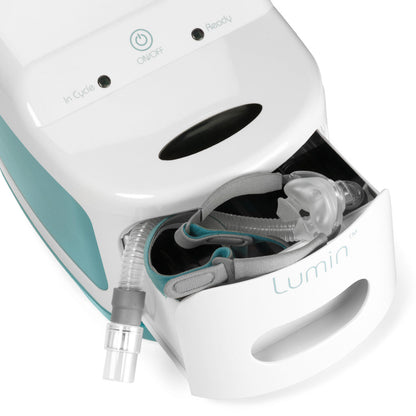 Close-up of a CPAP mask cushion and tubing tucked into the Lumin sanitizer's open drawer, seen from above