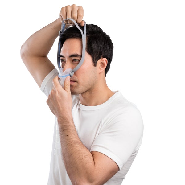 Man pulling the AirFit N30 headgear up and over his head while holding the cushion under his nose
