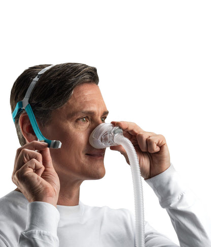 Photo of a man fitting the Nova Nasal, holding the cushion to his nose with the strap over his head