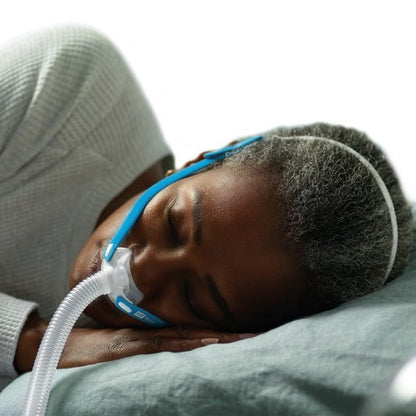 Photo of the Nova Micro worn by a woman asleep on her side, her cheek resting on the pillow