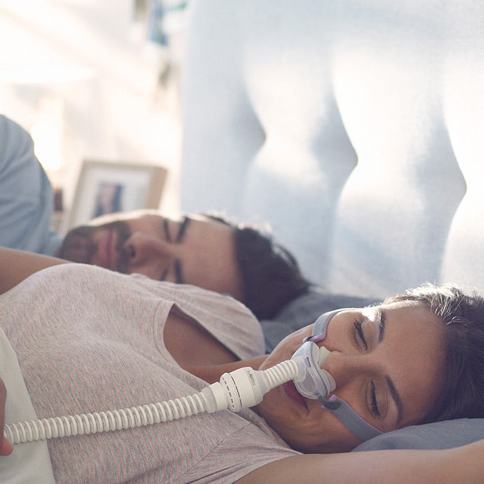 Photo of a woman sleeping on her back in the AirFit P10 for AirMini, her partner beside her