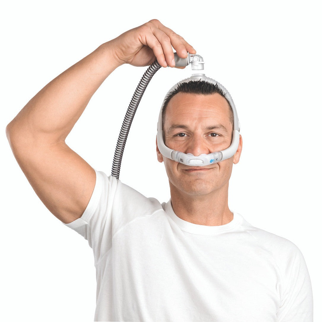Man wearing an AirFit P30i, lifting the tube that connects on top of his head