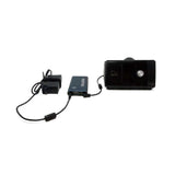 Angled view of the Pilot Flex battery in Dark Navy wired to a CPAP machine and its power adapter