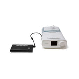Pilot Flex battery in Charcoal connected by its output cable to a Philips CPAP machine with humidifier