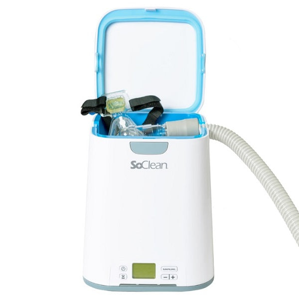 A SoClean 2 with the lid open and a CPAP mask and headgear inside, its hose connected at the side