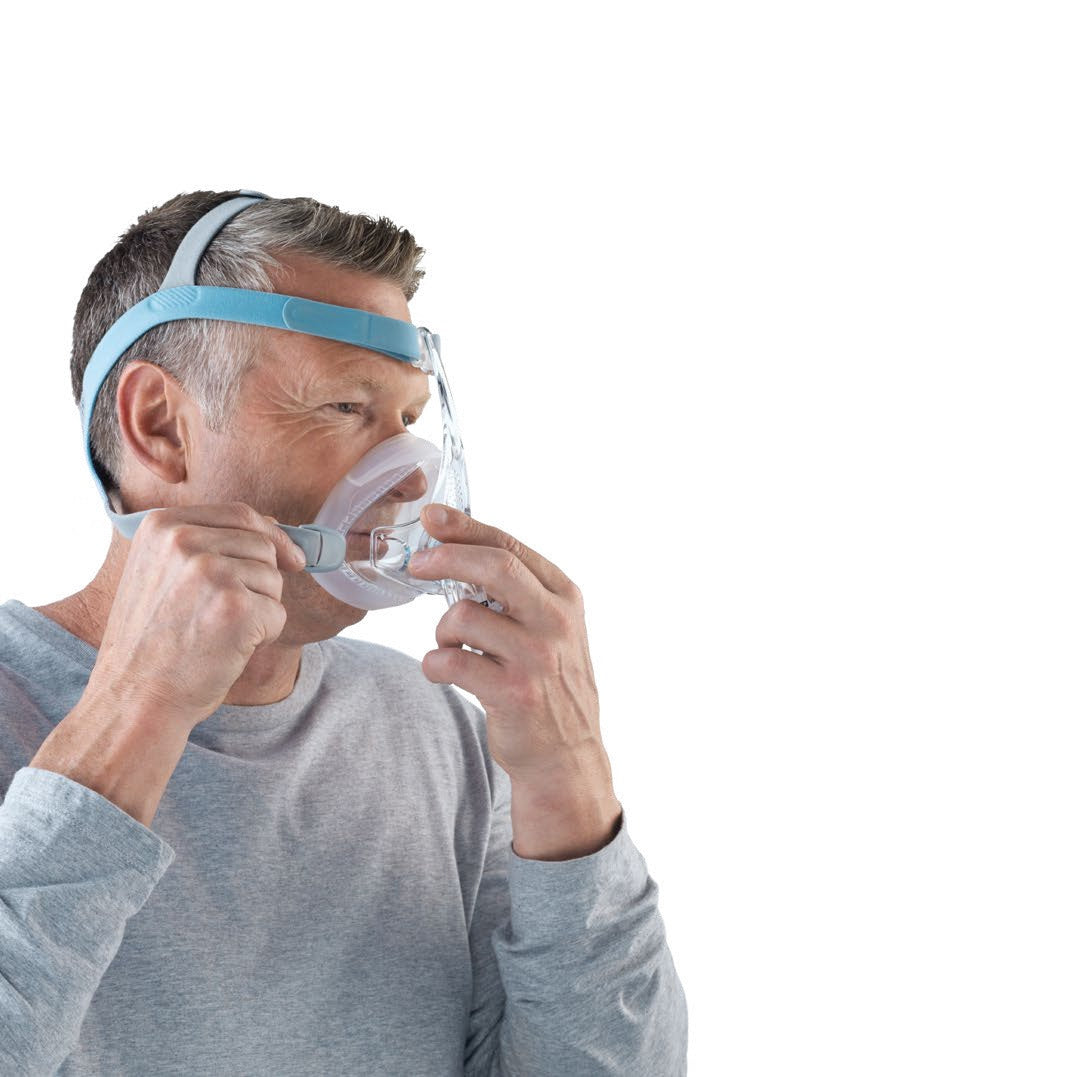 A man holding the Vitera mask to his face with both hands as he fits it, seen from the front