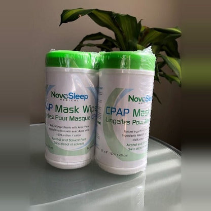 Two NovoSleep CPAP Mask Wipes canisters wrapped together as a pack of two, standing on a glass table
